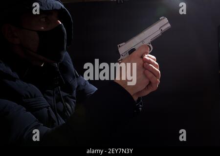 Thief with weapon and with mask in the dark. Stock Photo