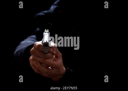 Thief in the dark pointing with weapon, isolated on black with copy space. Stock Photo