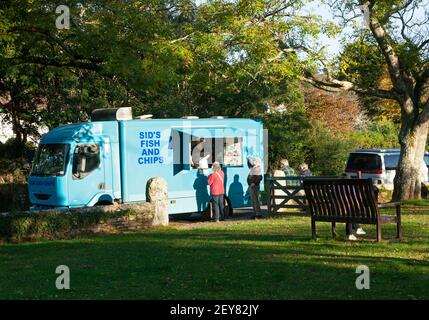 A fish and chip van serves a queue of senior customers at the village green of Gweek in Cornwall, UK Stock Photo