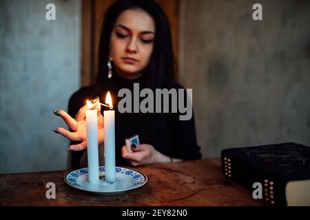 a girl fortune teller lights candles to predict the future. mystical ritual of communication with spirits Stock Photo