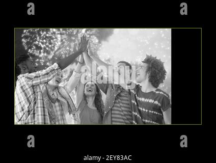 Black and white photo of group of friends high fiving in yellow frame on black background Stock Photo