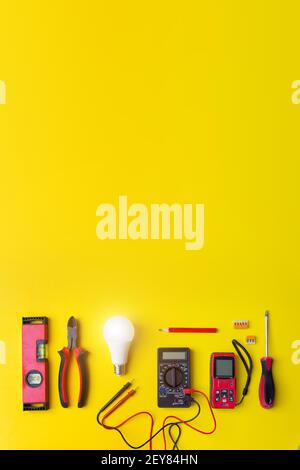 Different electrical tools on yellow background with shine. Components for use in electrical installations Stock Photo