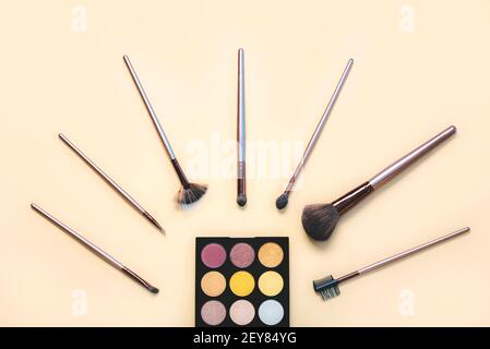 makeup brushes with eyeshadow palette on a beige background.Make Up Beauty Fashion concept Stock Photo