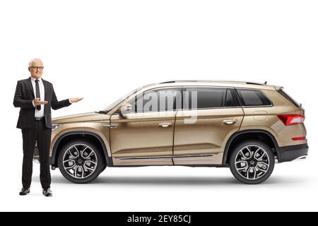Full length portrait of a middle aged man in a suit presenting a SUV isolated on white background Stock Photo