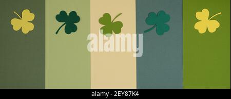 St Patricks Day wide format banner with paper shamrocks on striped green background. Flat lay, top view. Stock Photo