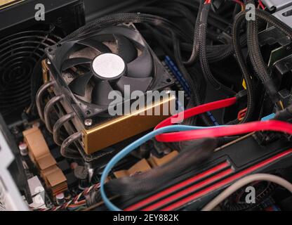 CPU fan with dust inside of a PC computer case with poor cable management. Close up. Stock Photo