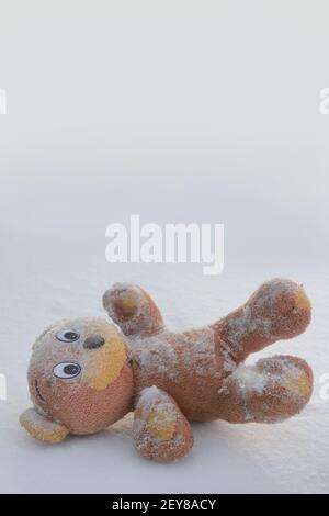 Soft toy bear lost in snow in winter. Concept of uselessness, past childhood. Stock Photo