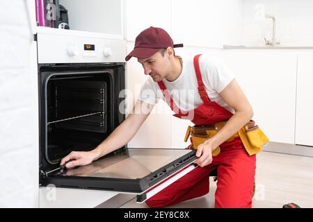 handsome young repairman fixing oven with screwdriver Stock Photo