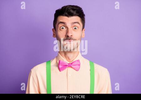 Photo of funny excited young guy wear yellow shirt biting lip ready to laugh isolated violet color background Stock Photo