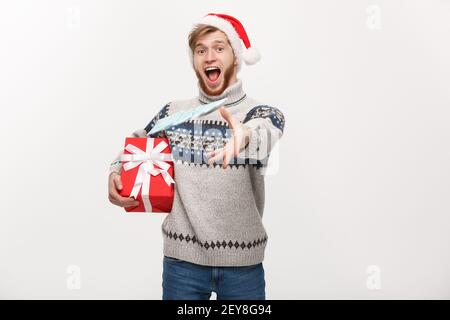 Holiday Concept - Young beard man holding christmas gift and throwing money to camera. Stock Photo