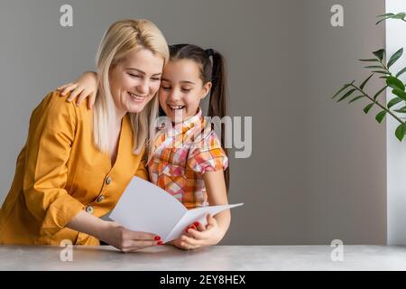 Happy mother's day. Child daughter congratulates moms and gives her a postcard. Stock Photo