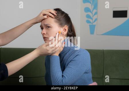 Image of girl getting check up by her friend while sitting on the sofa Stock Photo