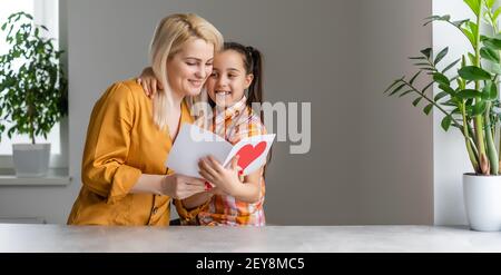 Happy mother's day. Child daughter congratulates moms and gives her a postcard. Stock Photo