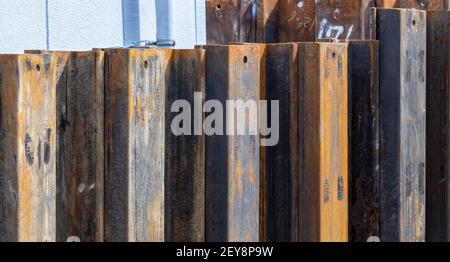 Rusty steel piles have been driven into the earth to create a steel barrier that keeps soil in its place without it collapsing into the dug out space Stock Photo