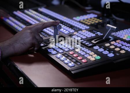 Hands on dissolve of Switcher buttons in studio TV station, Audio and Video Production Switcher of Television Broadcast Stock Photo