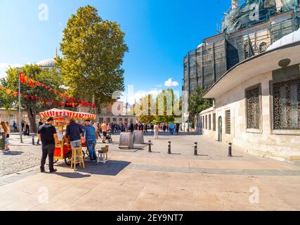 Local Turks enjoy a sunny day and grilled corn in downtown Istanbul Turkey near Eminonu district and bazaar. Stock Photo