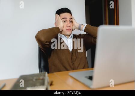 A portrait of an anxious young employee working on his laptop in the office Stock Photo