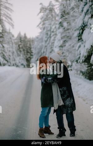 A beautiful couple kissing and sharing their love standing in the middle of a frozen road Stock Photo