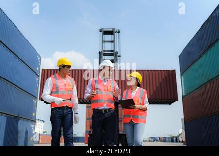 Asian foreman walking and explaining the various operations in the container depot terminal to worker. Stock Photo