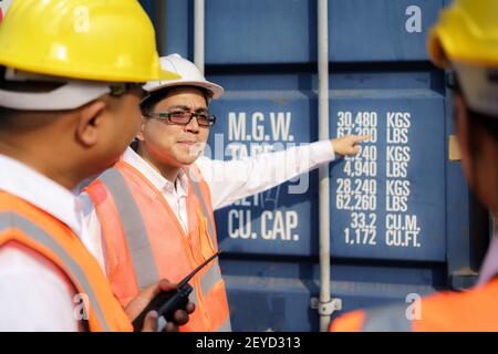 Asian foreman is explaining and teaching new training workers for various components of container to new inspection container worker. Stock Photo