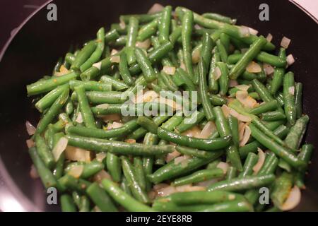 Cooking green beans with onions at home Stock Photo