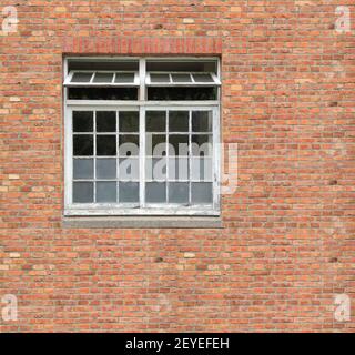 White painted wood arched window in a red brick wall Stock Photo