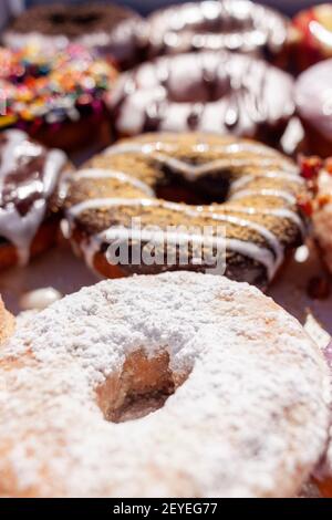Flat lay image of fresh made store bought donuts in paper box fresh out of the donut shop. An assortment with different flavors and toppings are packe Stock Photo