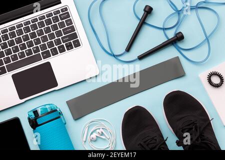 Flat lay top view of laptop with sport equipments on blue background. Healthy lifestyle online fitness concept Stock Photo