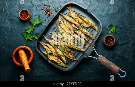 Fried capelin garnished with parsley and lemon zest in a pan Stock Photo