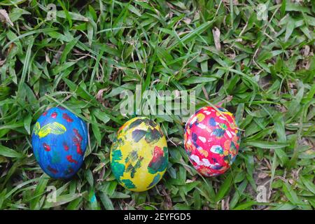 Easter Sunday concept. Three colorful eggs hidden on grass garden with copy space. Stock Photo