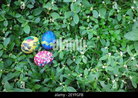 Easter Sunday concept. Three colorful eggs hidden on grass garden with copy space. Stock Photo