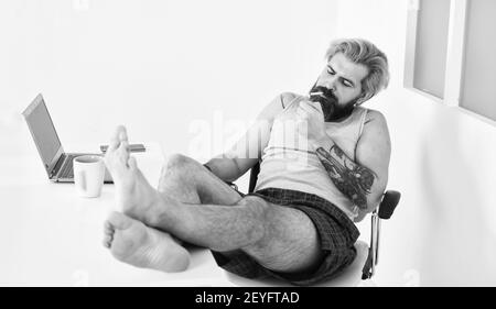 cigarette internet Barefoot man smoking cigarette and watching film on laptop screen at home.  cyber monday sale. alternative office freelance. home working online using  internet. free leisure time. modern job lifestyle Stock Photo -