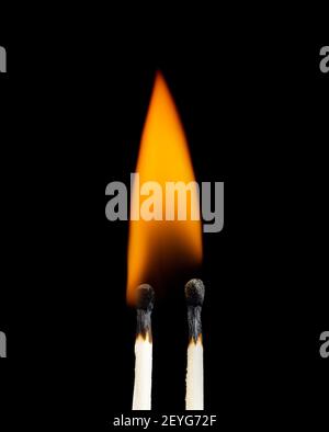 Close-up of two burning matchsticks against a black background. Stock Photo