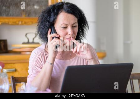 Woman talking on the phone Woman talking on the phone while working on the computer Stock Photo