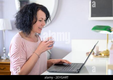 Woman is working on her computer and drinking a coffee Stock Photo