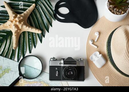 Travel flat lay. Camera,protective mask,headphones,magnifying glass on white background Stock Photo