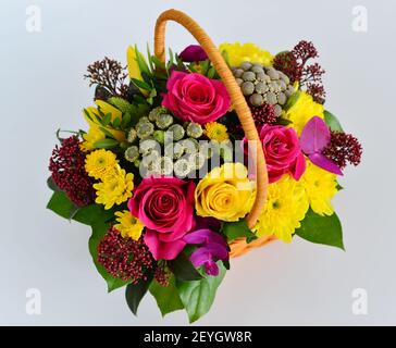 Beautiful flowers in wicker basket on  light background Stock Photo