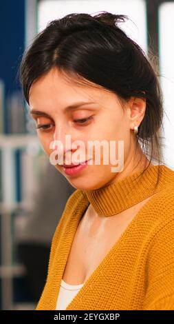 Young woman in casual clothing working at laptop sitting at desk in busy financial startup company while diverse team analyzes statistics data in modern office. Multiethnic team concentrated on work Stock Photo