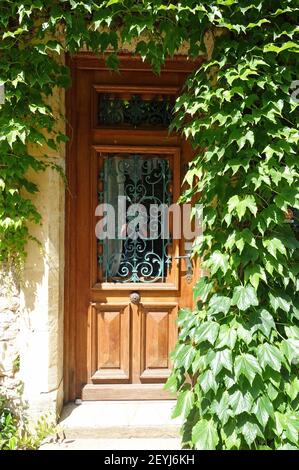 Recessed wooden front door surrounded by ivy Stock Photo