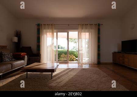Living room in the shade with natural light coming in through sliding doors Stock Photo
