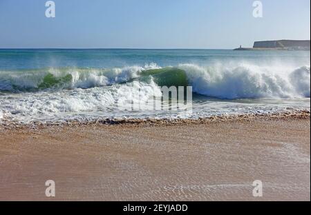 Waves crashing onto a sandy beach in the algarve Stock Photo