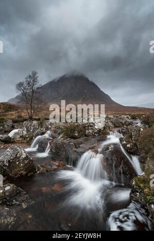 Stunning landscape image of Buachaille Etive Mor waterfall in Scottish highlands on a Winter morning with long exposure for smooth flowing water Stock Photo