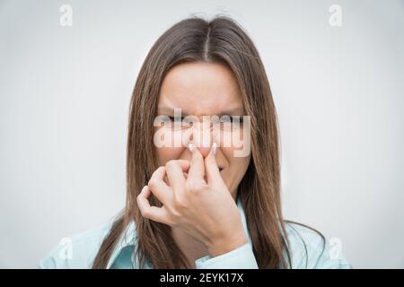 Woman smelling something stinky. Holding breath with fingers on her nose Stock Photo