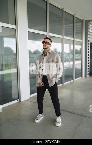 A young fashionable man wearing casual clothes and sunglasses posing outdoors Stock Photo