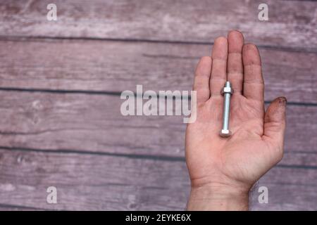 Bolt and nut. In the man's hand, smeared with work, lies a screw with a screwed nut. empty space, Stock Photo