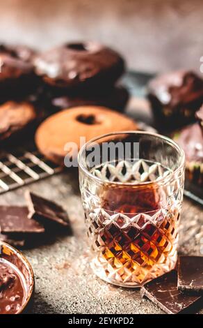 Whiskey on a background of chocolate donuts and the chocolate. Stock Photo