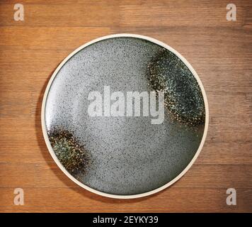 Black round plate on brown wooden table above top view Stock Photo