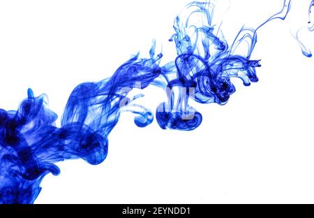 Blue ink injected into water from syringe, colour mixing with water creating abstract shapes, white background Stock Photo