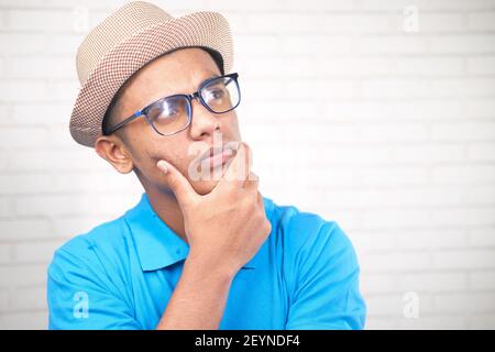 thoughtful young man with hat and eyeglass looking away  Stock Photo