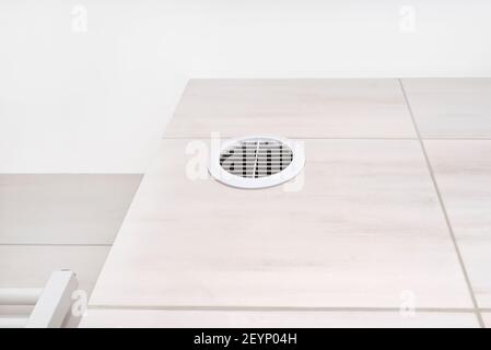 White grille in the wall, in the bathroom, from the gravity ventilation in the chimney of the house. Stock Photo